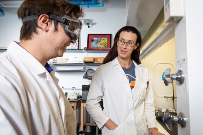 Professor and student in lab coats discuss results in lab