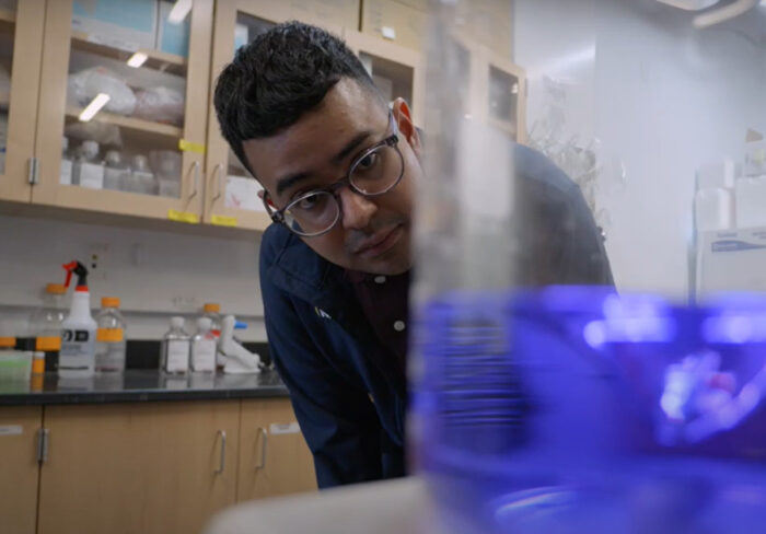 student examines beaker of purple liquid in science lab