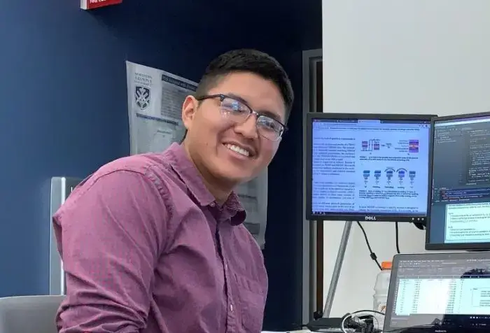 Portrait of Taylor Begaye smiling in front of computer