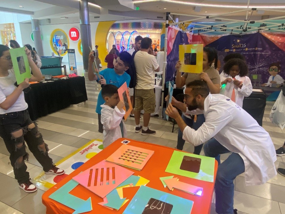 grad students work with small children in classroom with construction paper