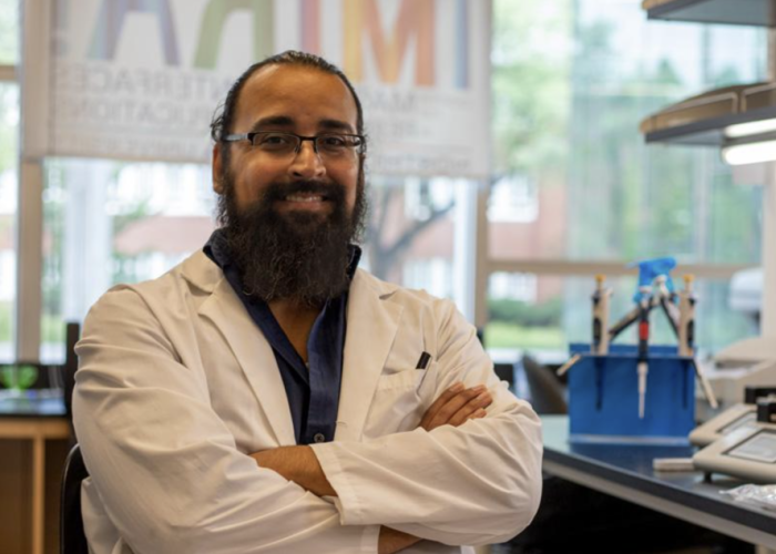 Jorge Muñoz, a scientist with a beard and glasses, poses with his arms crossed in a well-lit science lab.