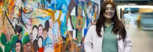 REU Student Intern Marian Yadira Jimenez stands in front of colorful mural.