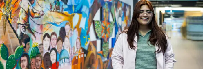 REU Student Intern Marian Yadira Jimenez stands in front of colorful mural.